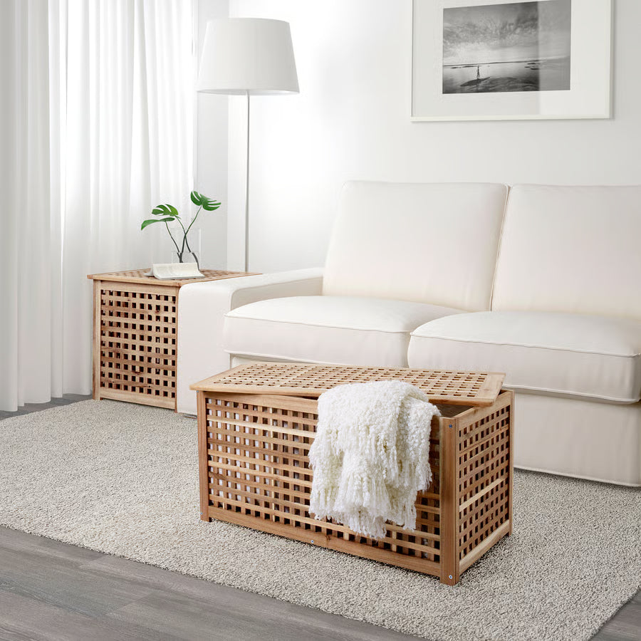 Wooden storage bench with a white blanket in a living room setting.